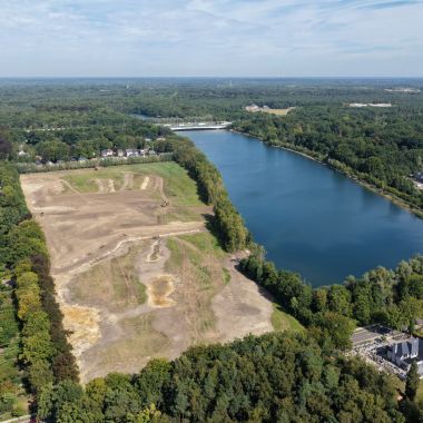Luchtfoto van een grote, min of meer rechthoekige waterplas en een afgegraven vlakte van ongeveer dezelfde grootte er net naast. Tussen waterplas en vlakte staat een bomenrij, die op twee plaatsen opengemaakt is. 