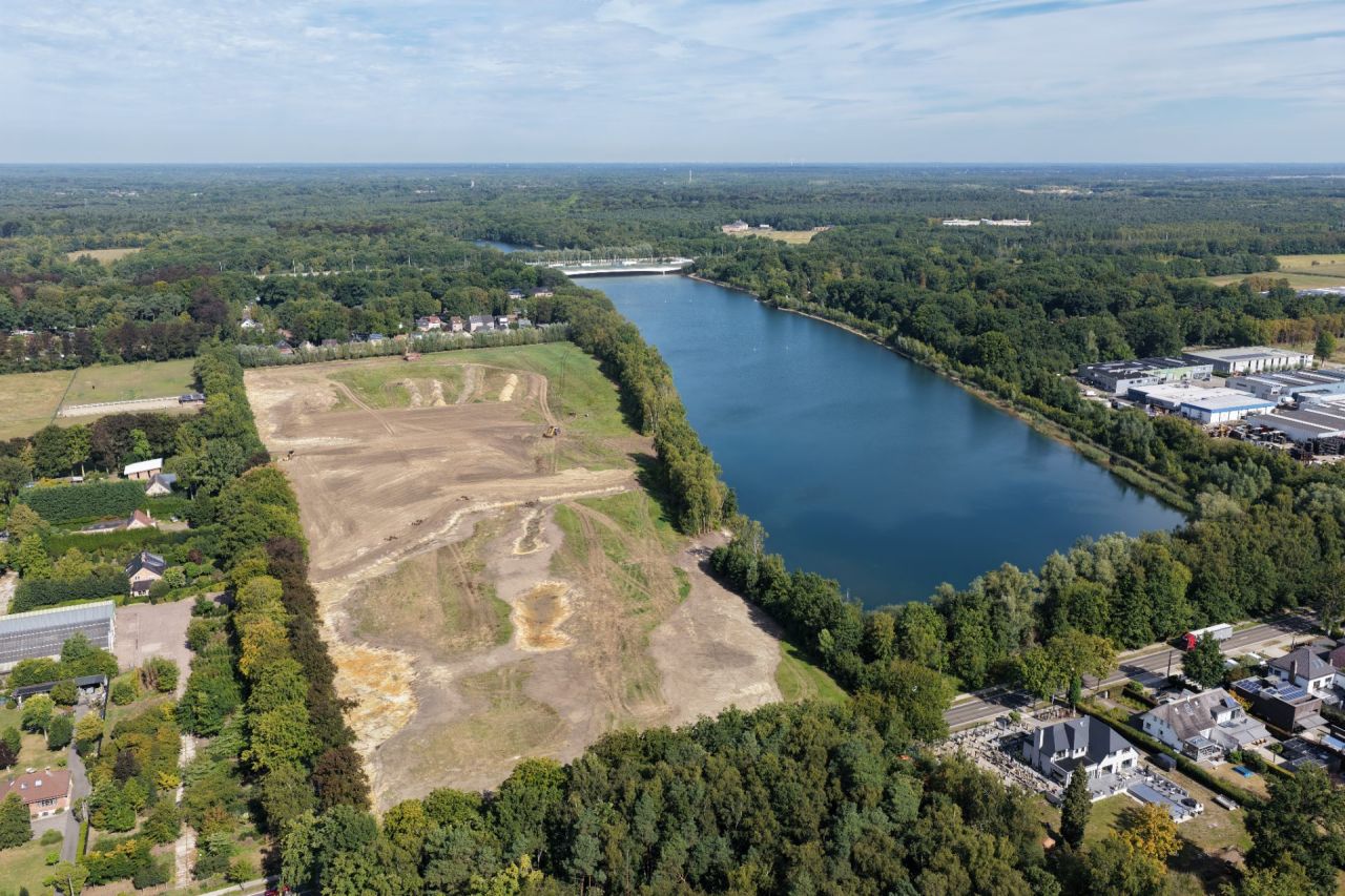 Luchtfoto van een grote, min of meer rechthoekige waterplas en een afgegraven vlakte van ongeveer dezelfde grootte er net naast. Tussen waterplas en vlakte staat een bomenrij, die op twee plaatsen opengemaakt is.