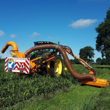 Een gespecialiseerde landbouwmachine maait de gras- en kruidenrand rond een akker. 