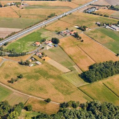Luchtfoto van het landbouwgebied Corsendonck in Oud-Turnhout, genomen in september 2021. De foto toont vergeelde velden, enkele bosacthige gebieden, een berbindingsbaan en enkele verspreide woningen en andere gebouwen. . 