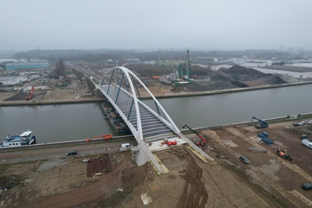 Een luchtfoto van de net geplaatste Hoogboombrug over het Albertkanaal. Onderaan de oever van Schoten, bovenaan de oever van Wijnegem. Het wegdek en de onmiddellijke omgeving van de brug zijn nog onafgewerkt.