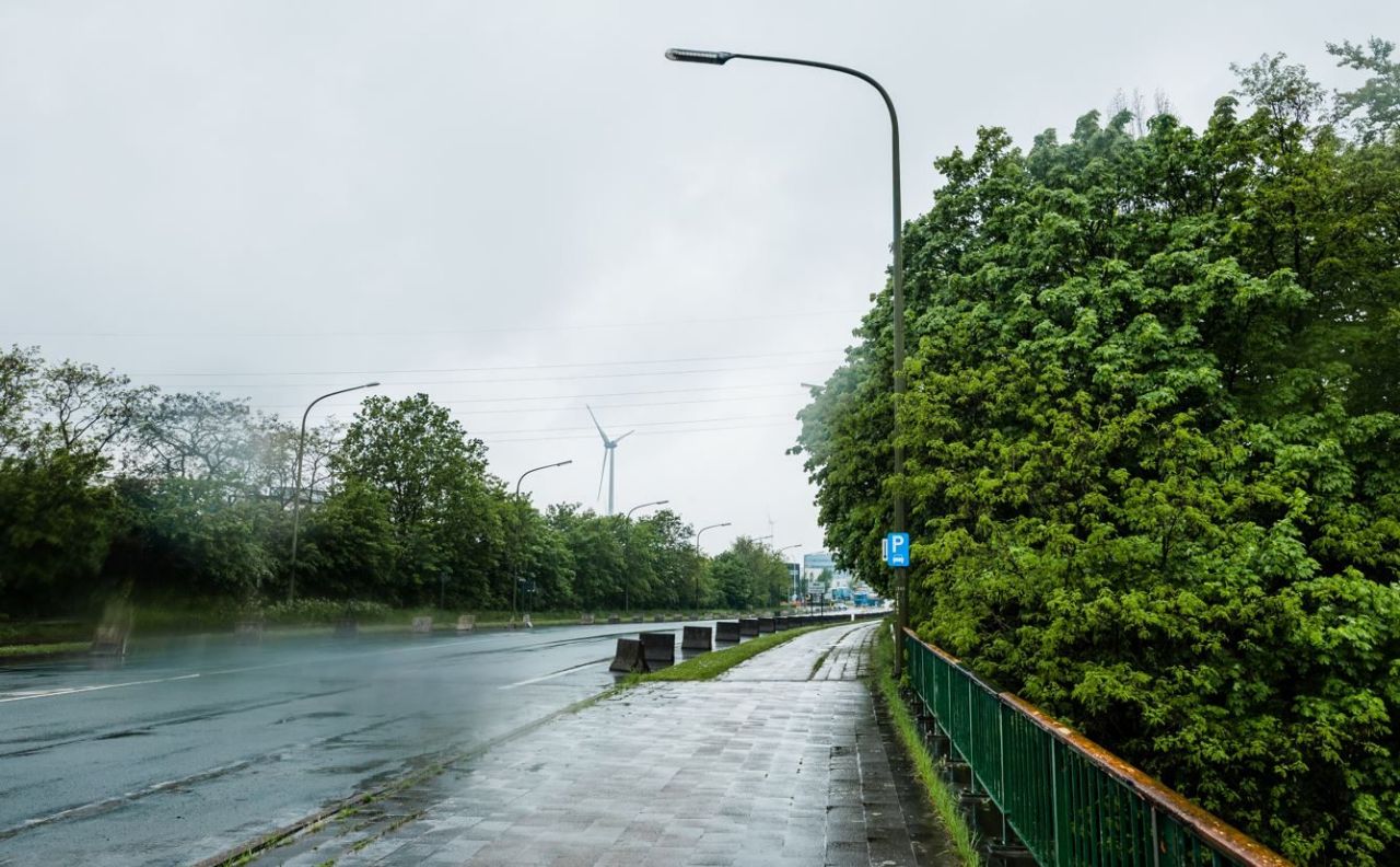 De Continentaalbrug in Ekeren. Een brede, lege, natgeregende brug zonder verkeer. De parkeerstroken zijn afgesloten met betonnen jerseyblokken.