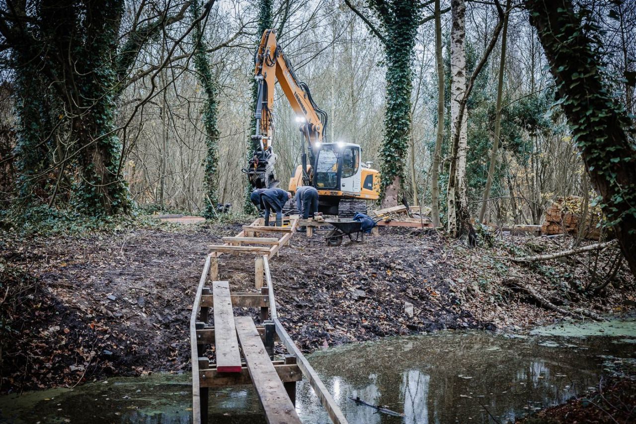 DownloadCheckoutProperties(p)Edit(e)AnnotateTo CollectionMove(m)Quick PublishManage PublicationClose Een vlonderpad in aanbouw over een waterloop in een bosomgeving. Arbeiders werken aan het vlonderpad, achter hen staat een grote graafkraan, met enkele felle lichten.