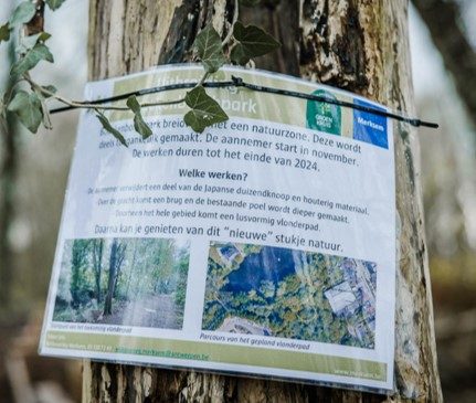 Een geplastifieerde A4 met informatie over de werken in Bouckenborgh is bevestigd rond de stam van een boom.
