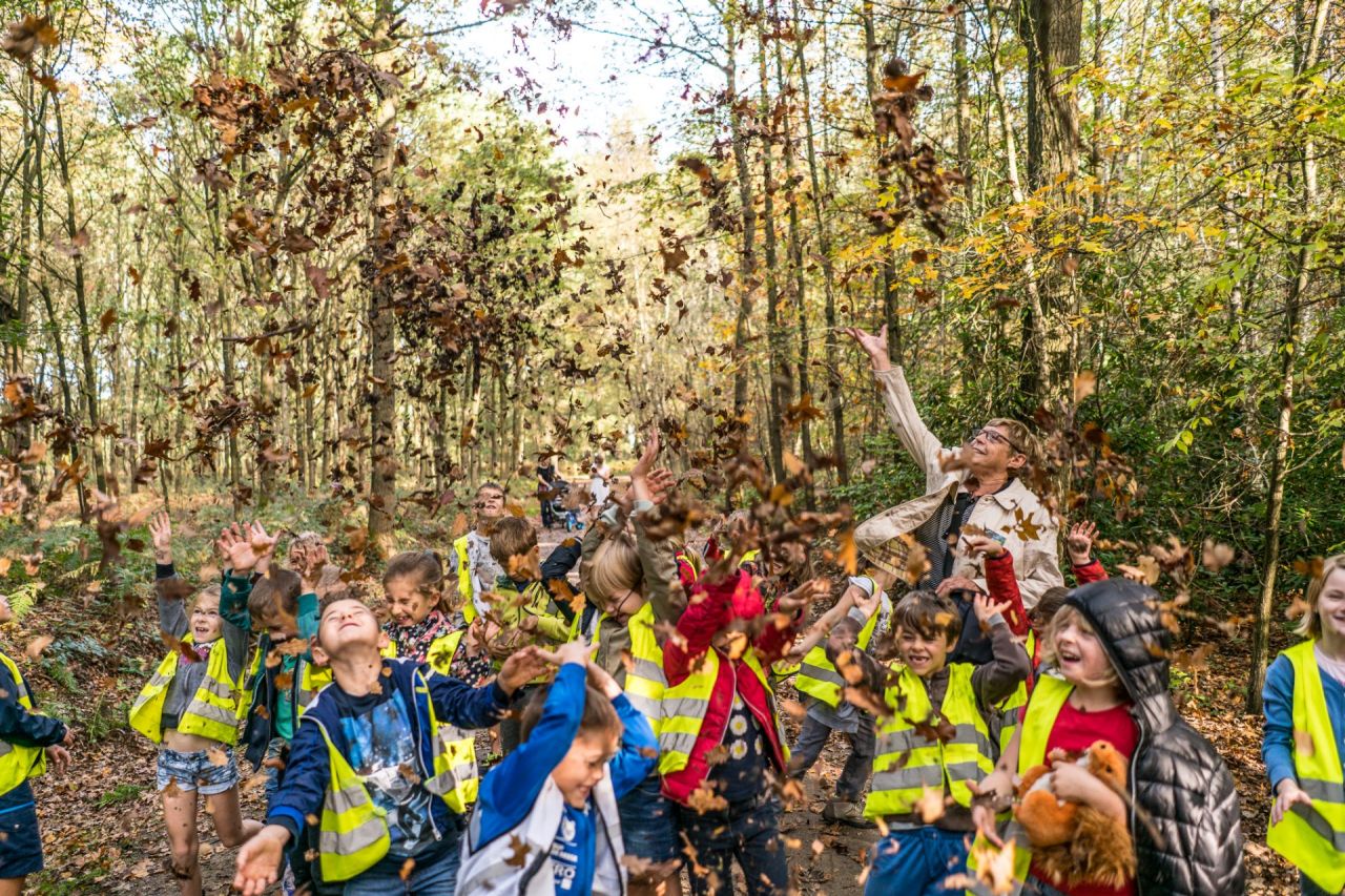 Kinderen gooien bladeren op in de herfst