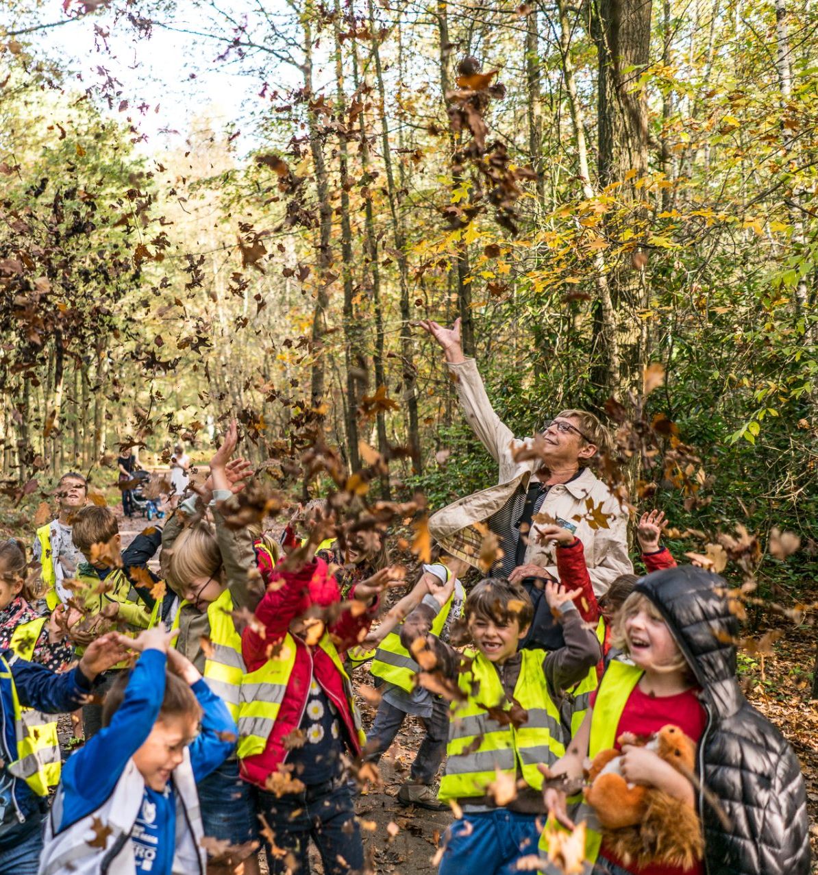 Kinderen gooien bladeren op in de herfst