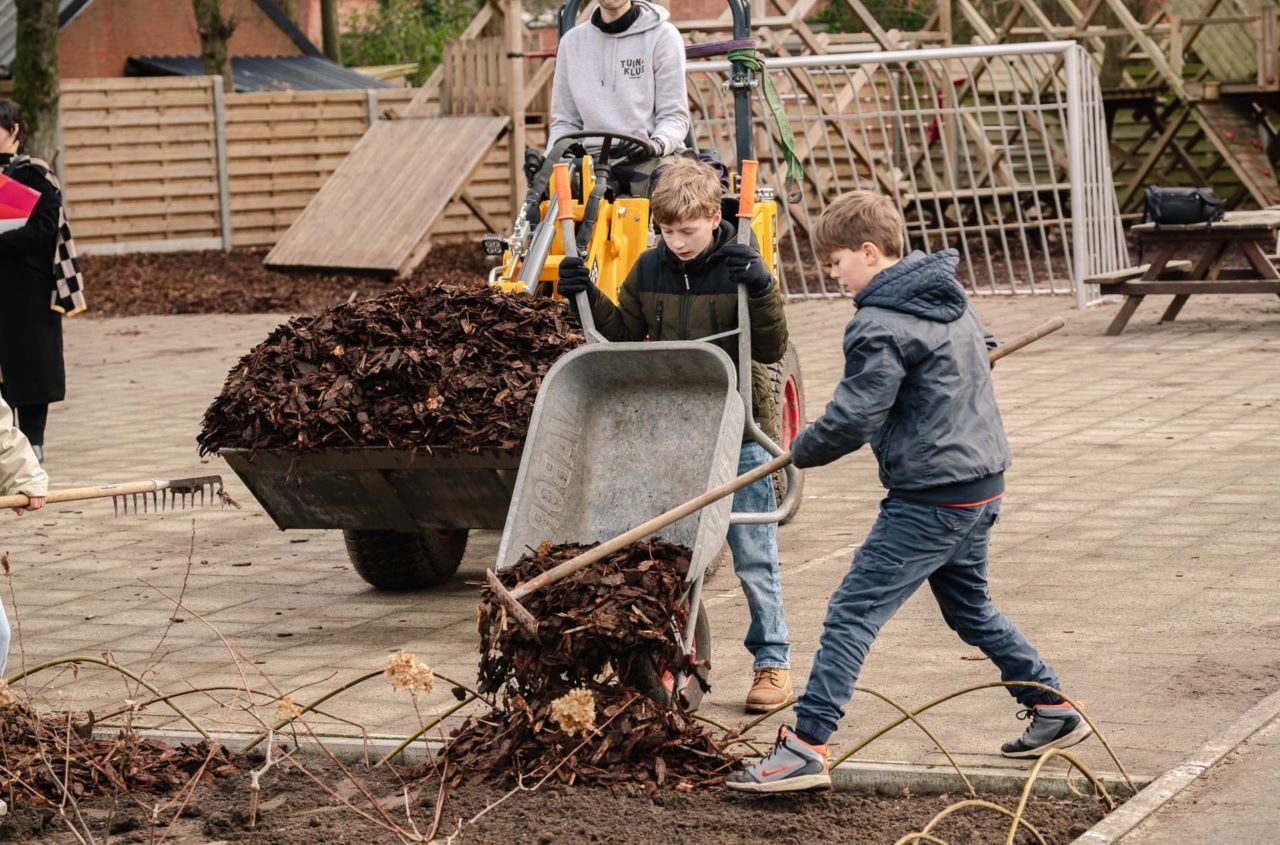 Leerlingen storten boomschors en bladeren uit in hun Groene Oase