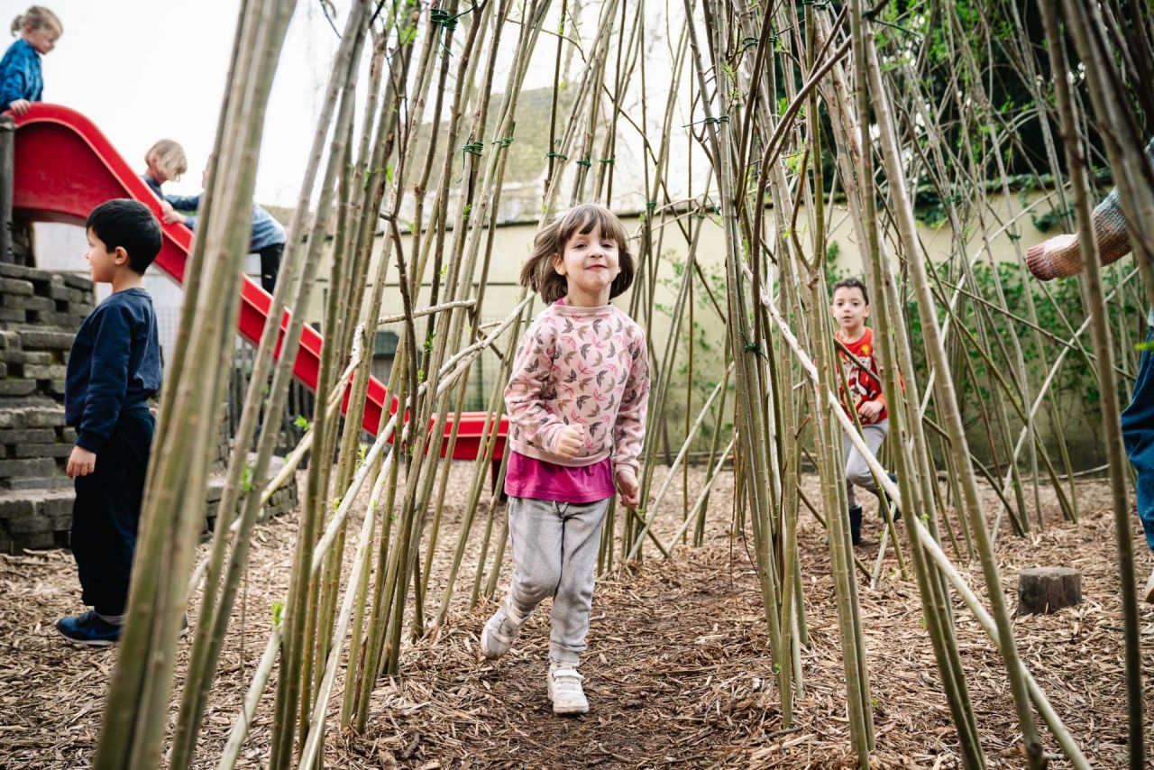 Leerlingen lopen door een wilgentunnel