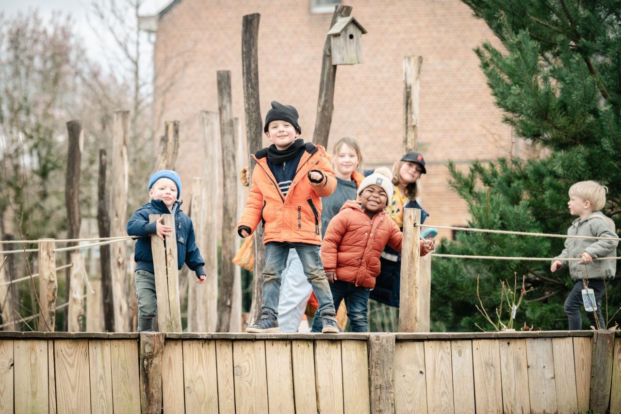 Kleine kinderen tonen blij hun buitenklas op hun speelplaats, hun Groene Oase.