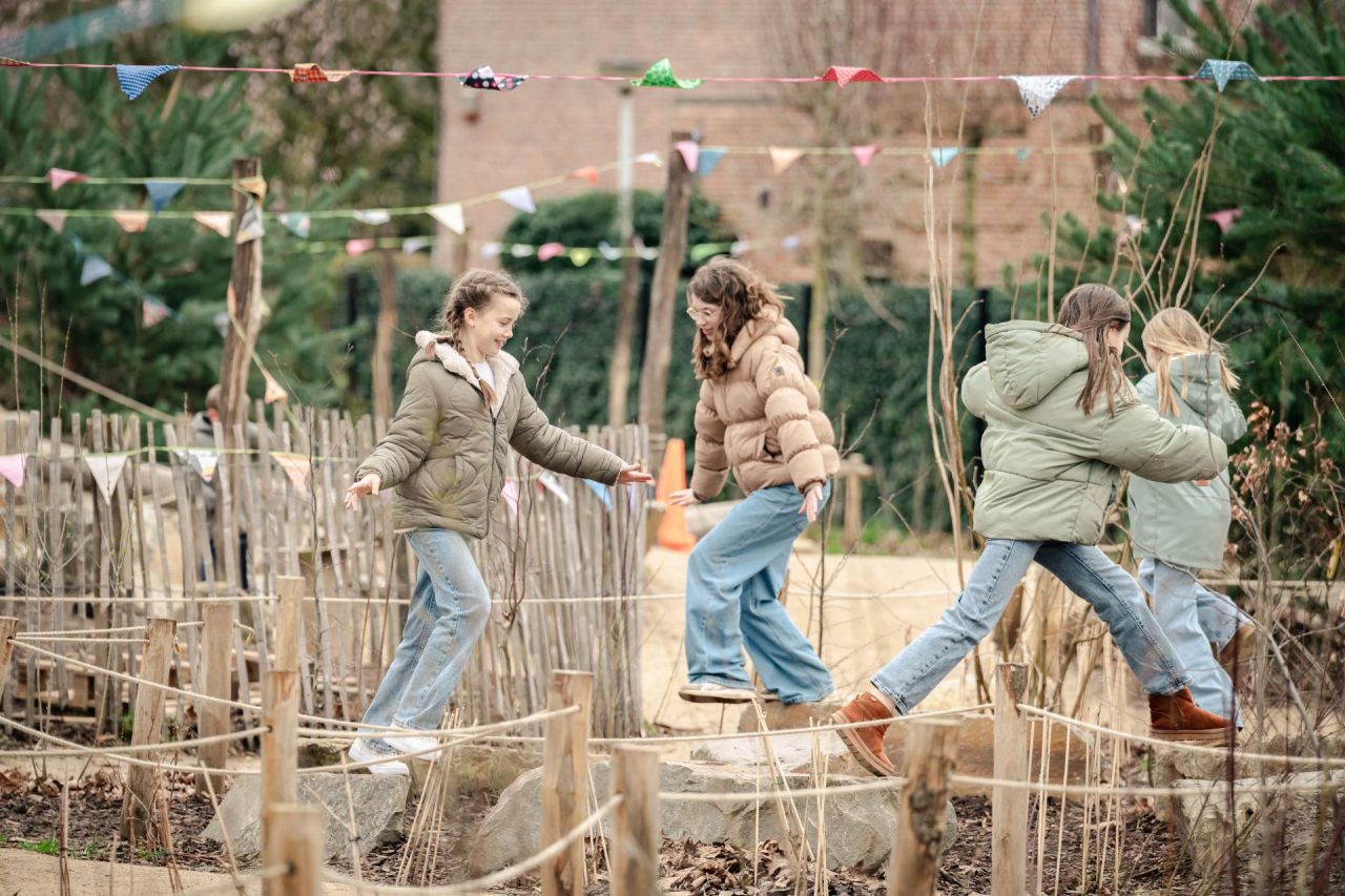 Kinderen springen van steen tot steen in de Groene Oase van De Springplank in Broechem