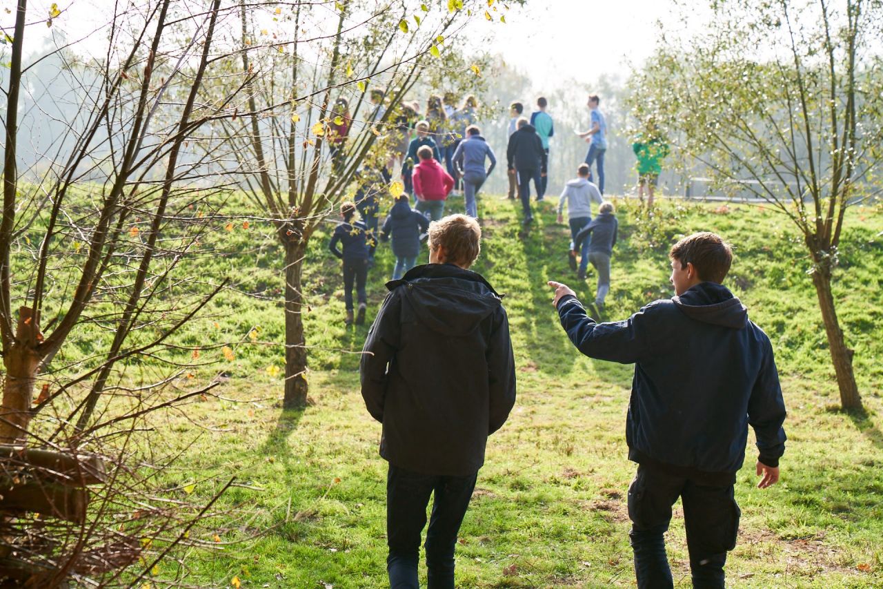 Begeleider en leerlingen in buitenklas